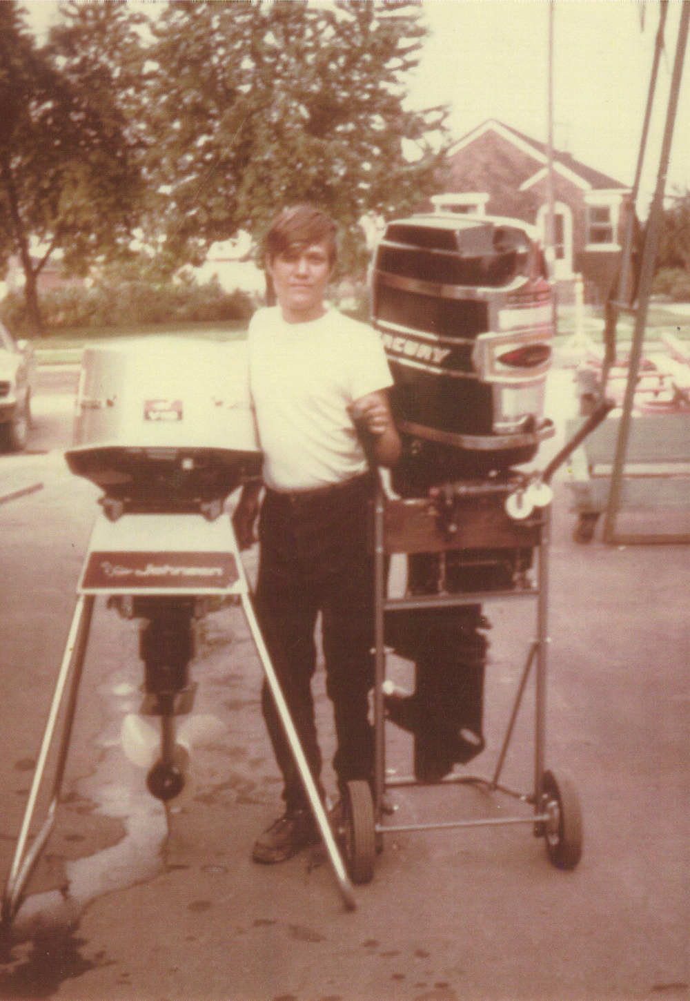 1969 - Paul Brazeau stands next to a Johnson and Mercury outboard (age 15)